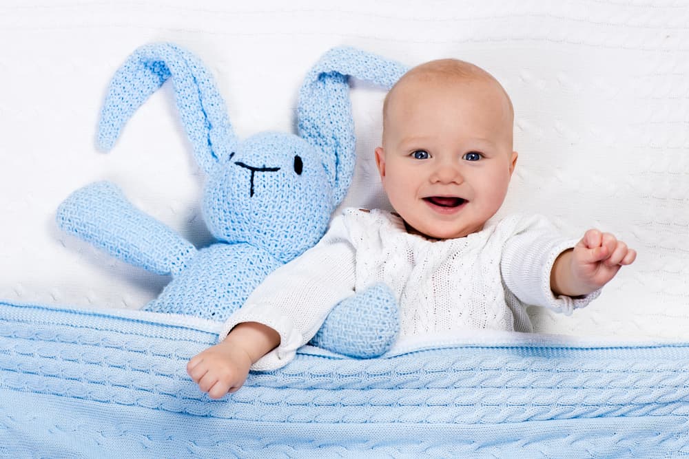 A baby smiling on the bed