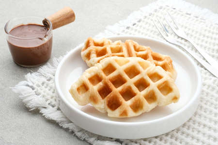 Plain croissant waffle or croffle with chocolate sauce served in plate on grey background. close up. Stock Photo