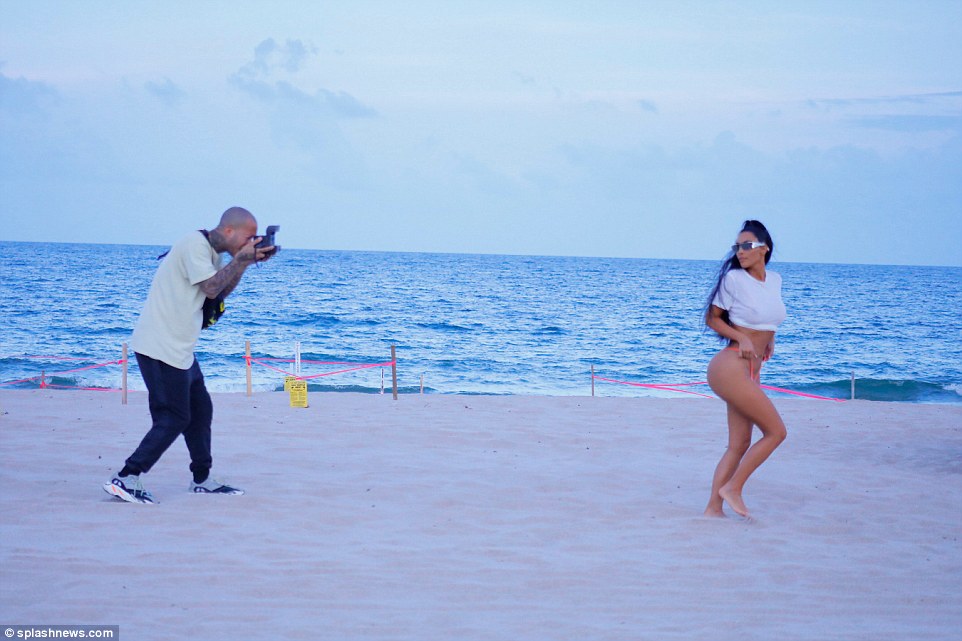 Strike a pose: Kim went accessory free as she walked around the idyllic beach barefoot and added just a pair of futuristic-looking silver metallic sunglasses