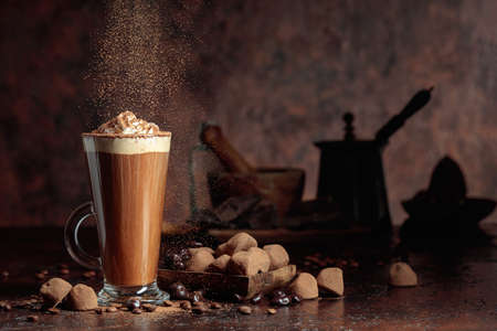 Truffles and a glass of hot chocolate. in the background silhouette of kitchen utensils.