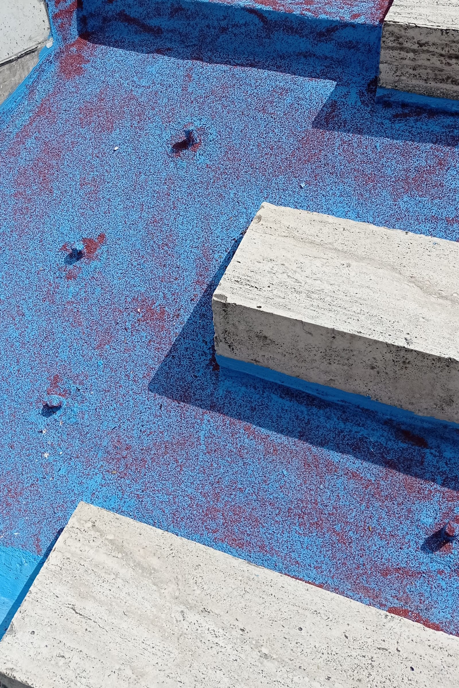 Sanding in the way - red sand is dispersed on a blue surface between stairs - red sand, blue paint - paul lahana