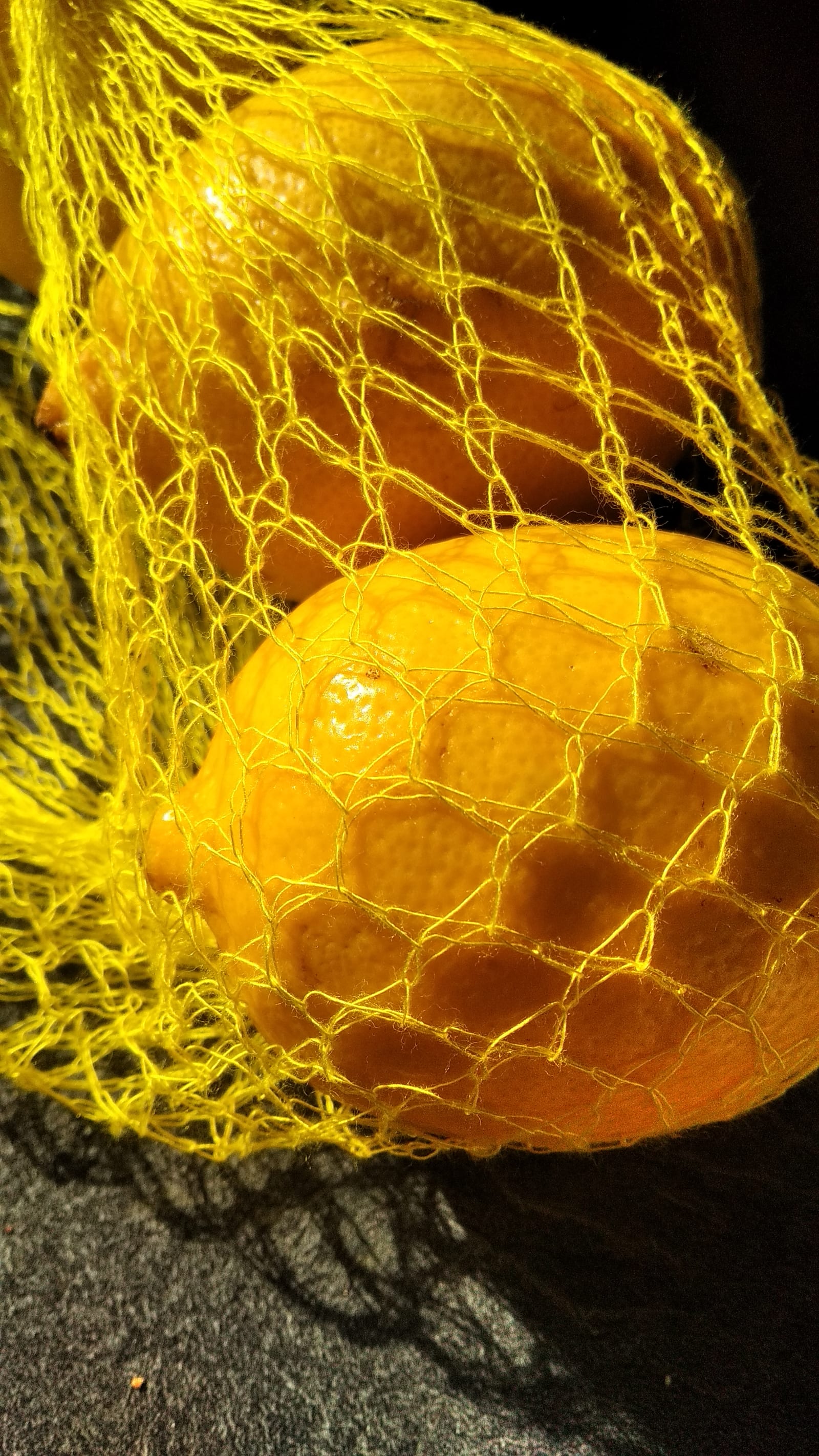 nets and lemons - A net made of yellow wire is holding lemons on a dark table - yellow wire, lemons (3) - paul lahana