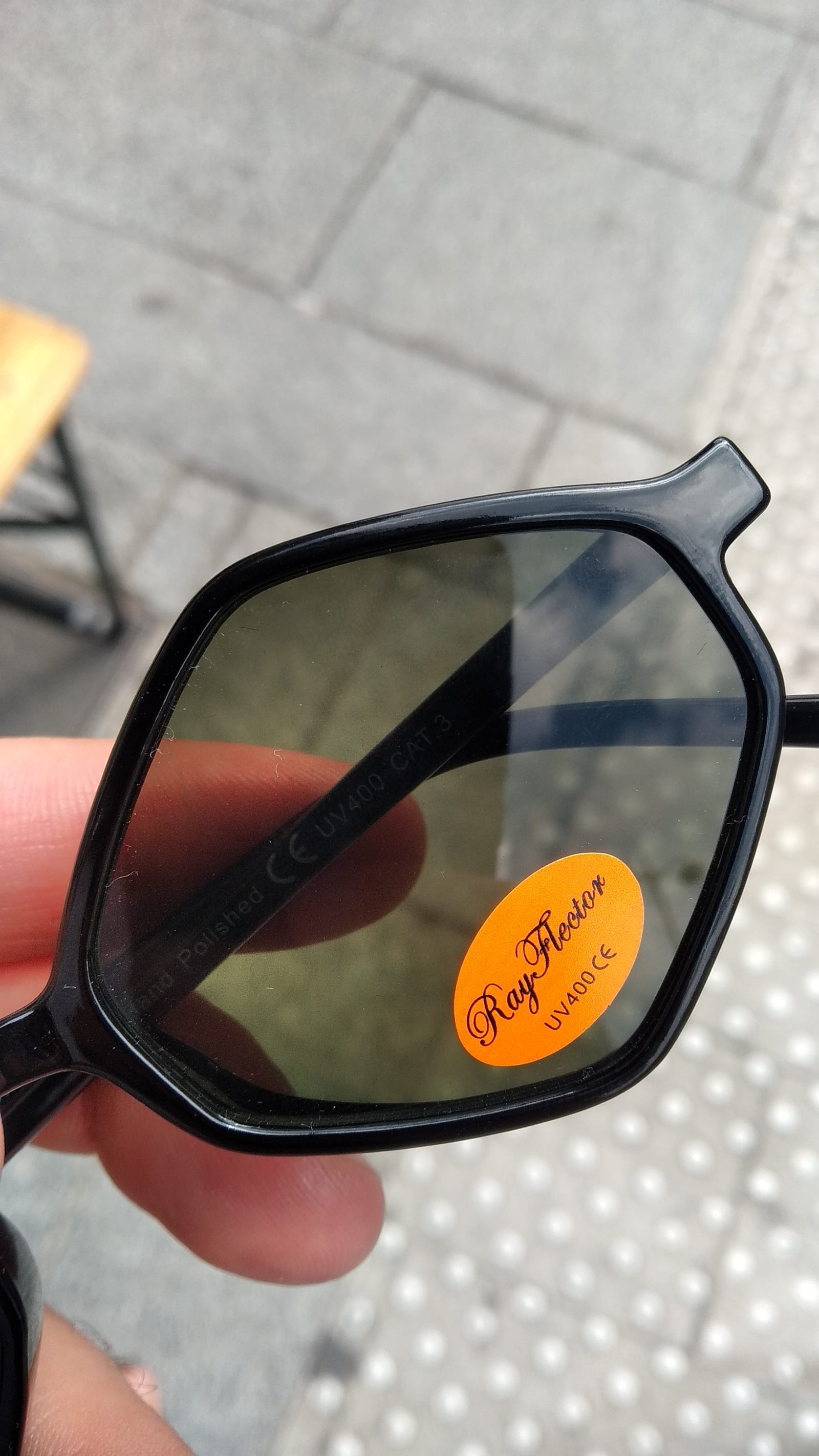 Charles - An orange sticker stuck on sun glasses says "Ray Flector"  - sun glasses, sticker - paul lahana