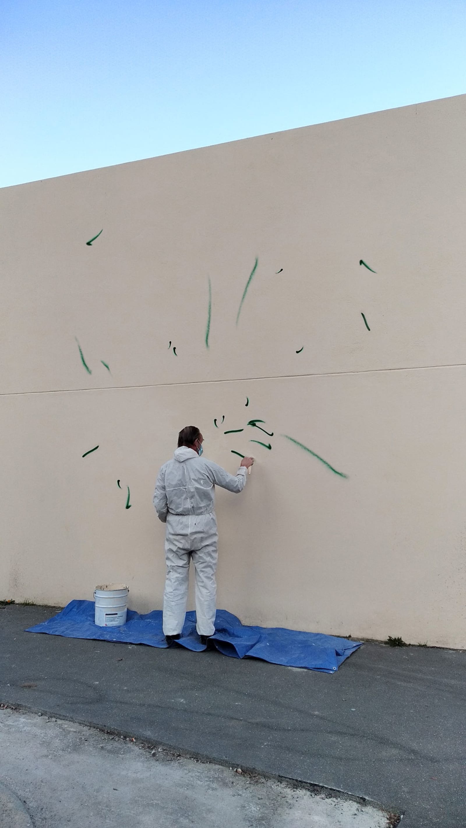 self-portrait (but with this dude instead of me) - an artist is painting a wall with many tiny graffiti - artist, spray paint, wall, graffiti - paul lahana