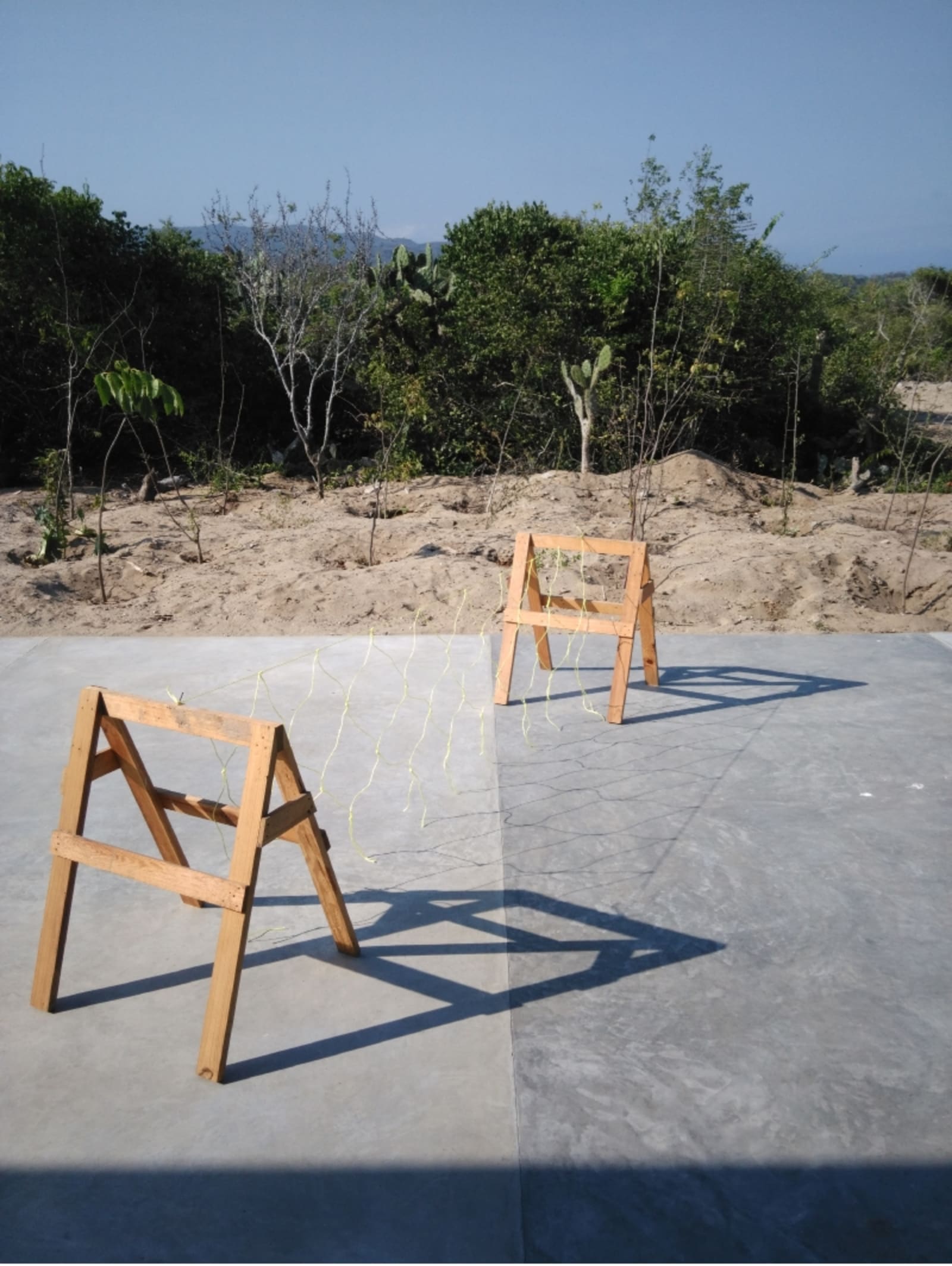 vaulting - a yellow net made of thin polyester cord is attached between two sawhorses in casa wabi - sawhorses, yellow cord - paul lahana