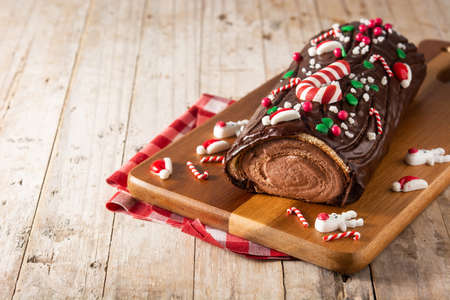 Chocolate yule log christmas cake on wooden table