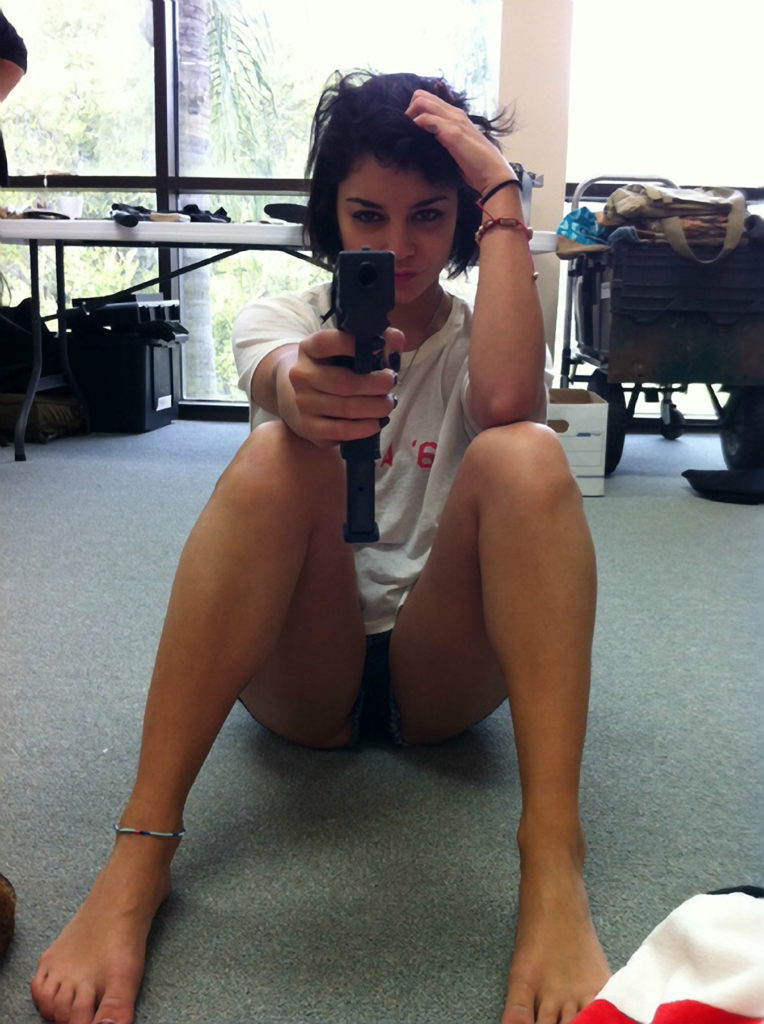 The petite actress holding gun in white t-shirt