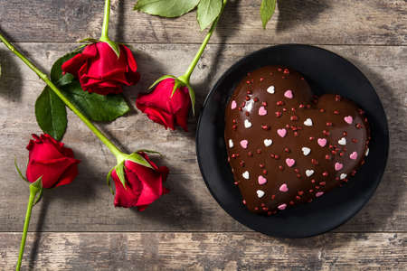 Heart shaped cake and red roses for valentine's day or mother's day on wooden table