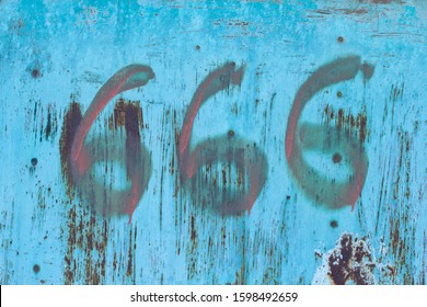 No. 666. The number three sixes in red paint on an old rusty blue surface. Number six hundred sixty six on a ragged metal surface.