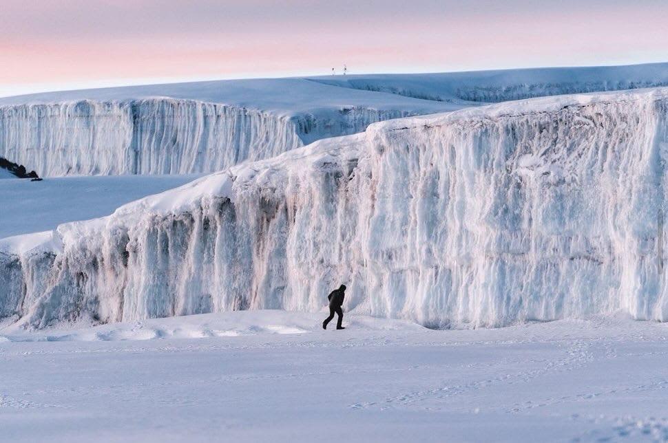 Trekkers camping at Mawenzi Tarn with dramatic Mawenzi Peak reflecting in alpine lake
