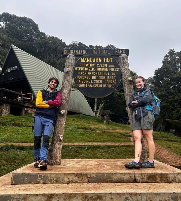 Hikers walking through Kilimanjaro’s rainforest along Marangu Route with mountain peaks visible