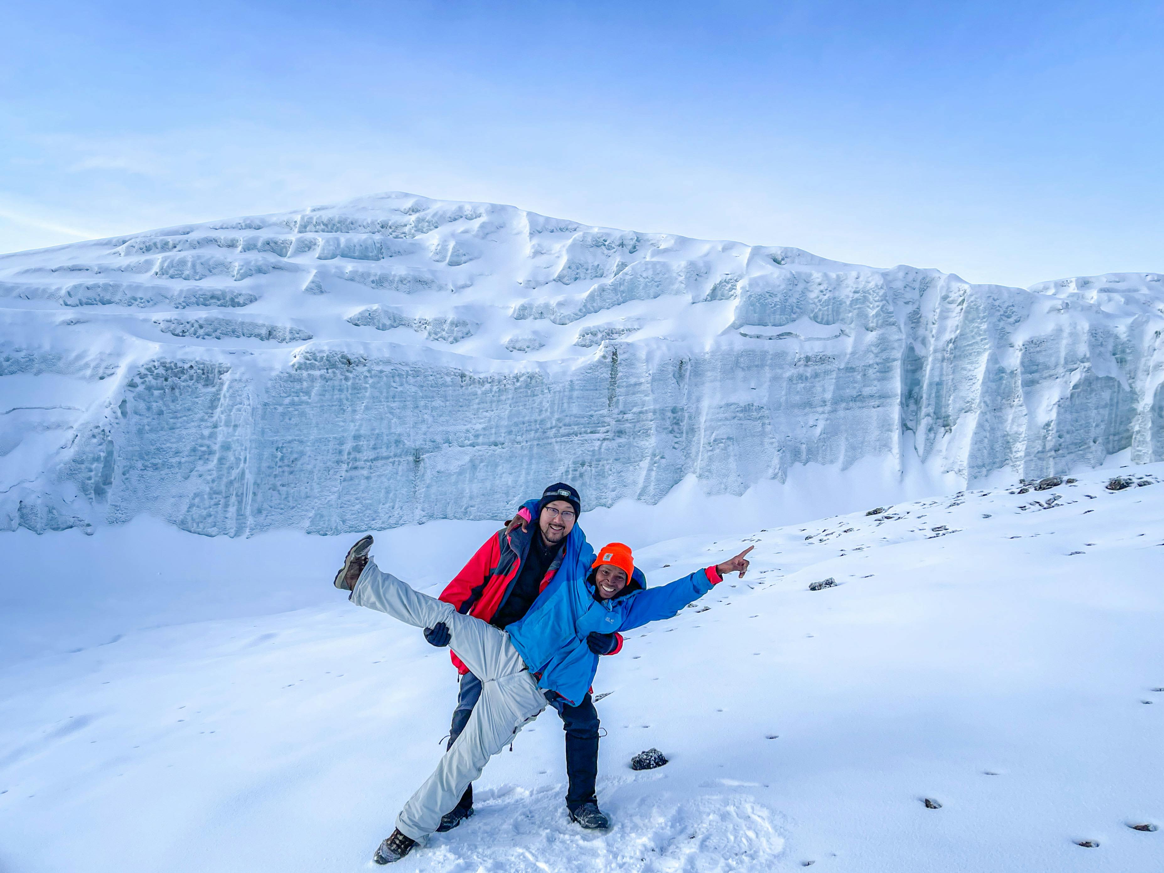 Happy tourist celebrating reaching the summit of mount kilimanjaro on a Lemosho rpute climbing tour"