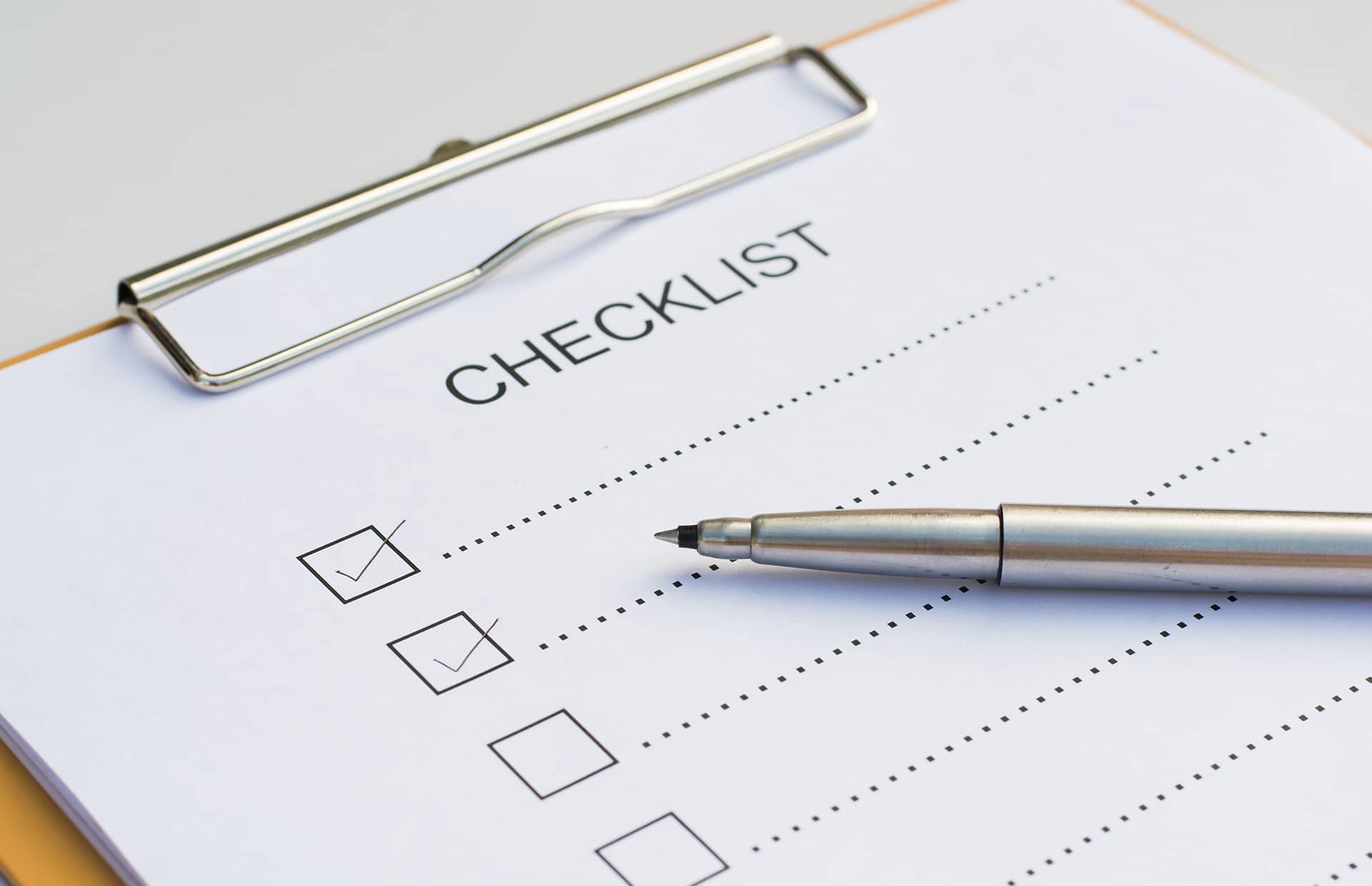 Checklist concept - checklist, paper and a pen with checklist word on wooden table