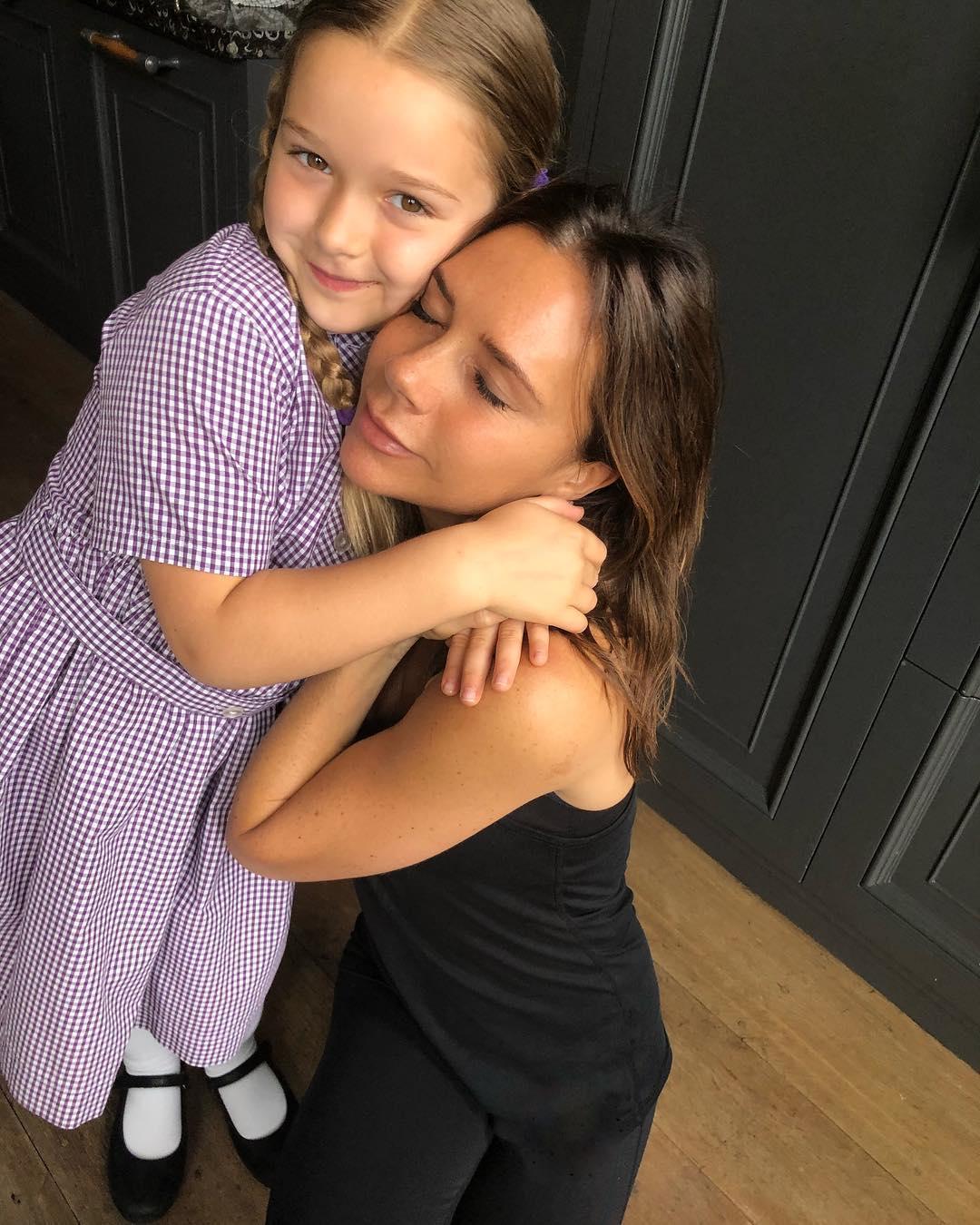 Mum's the word ... Victoria enjoys a hug from daughter Harper, writing on Friday that they 'loved and missed' husband David
