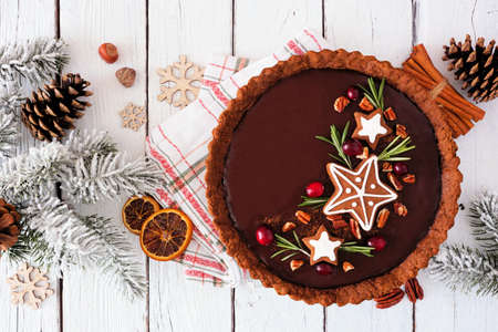 Christmas chocolate gingerbread tart. overhead view table scene against a white wood background. holiday baking concept.