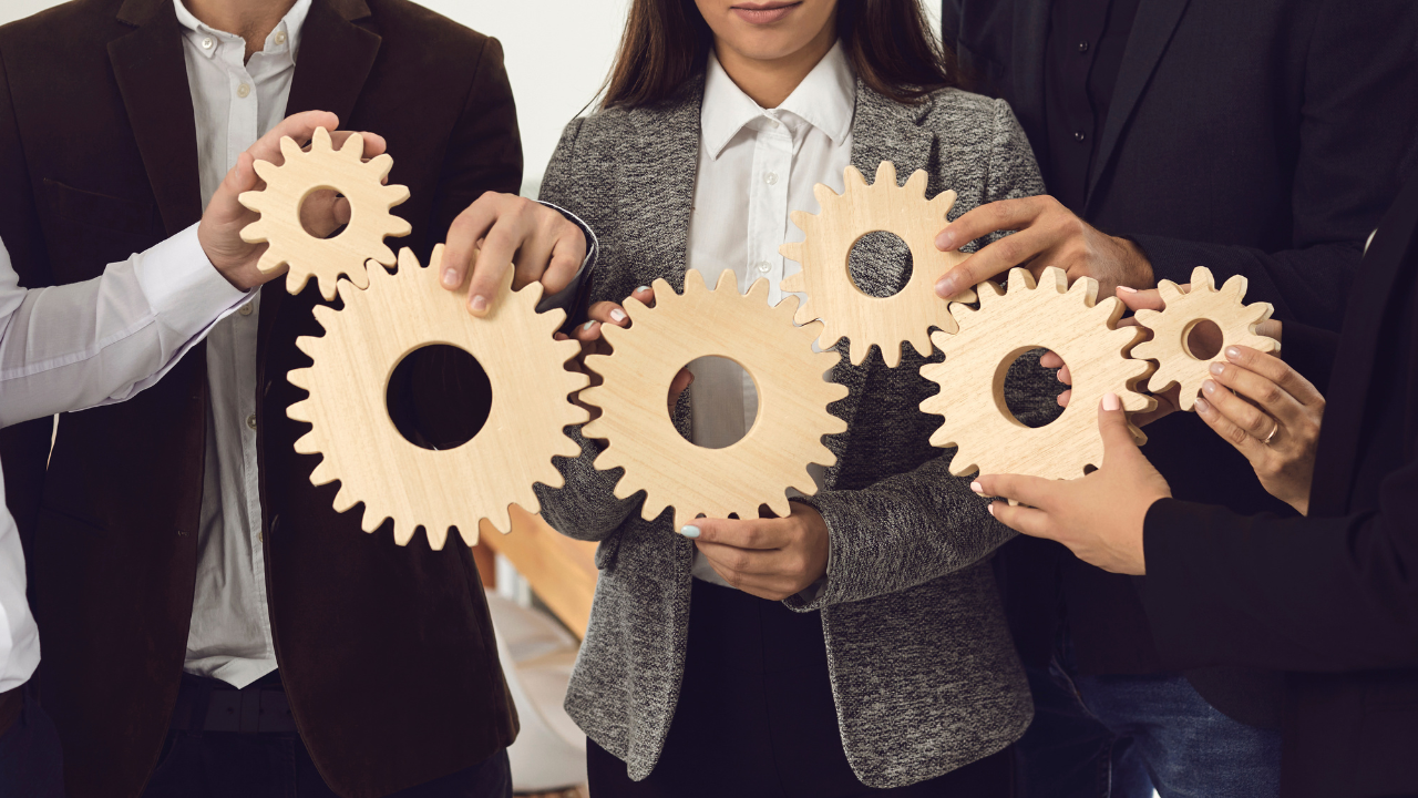 corporate people holding cogwheels together to make it work in one mechanism