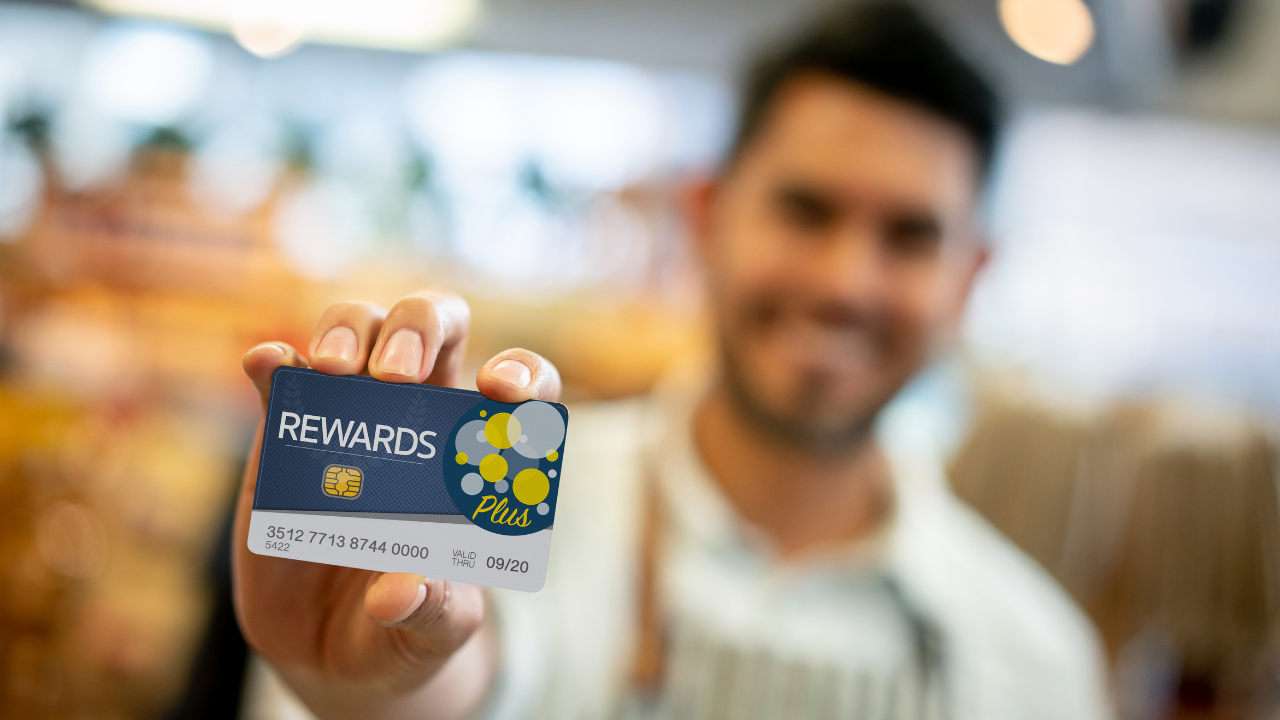 Happy vendor holding a Cash Rewards card for loyal customers