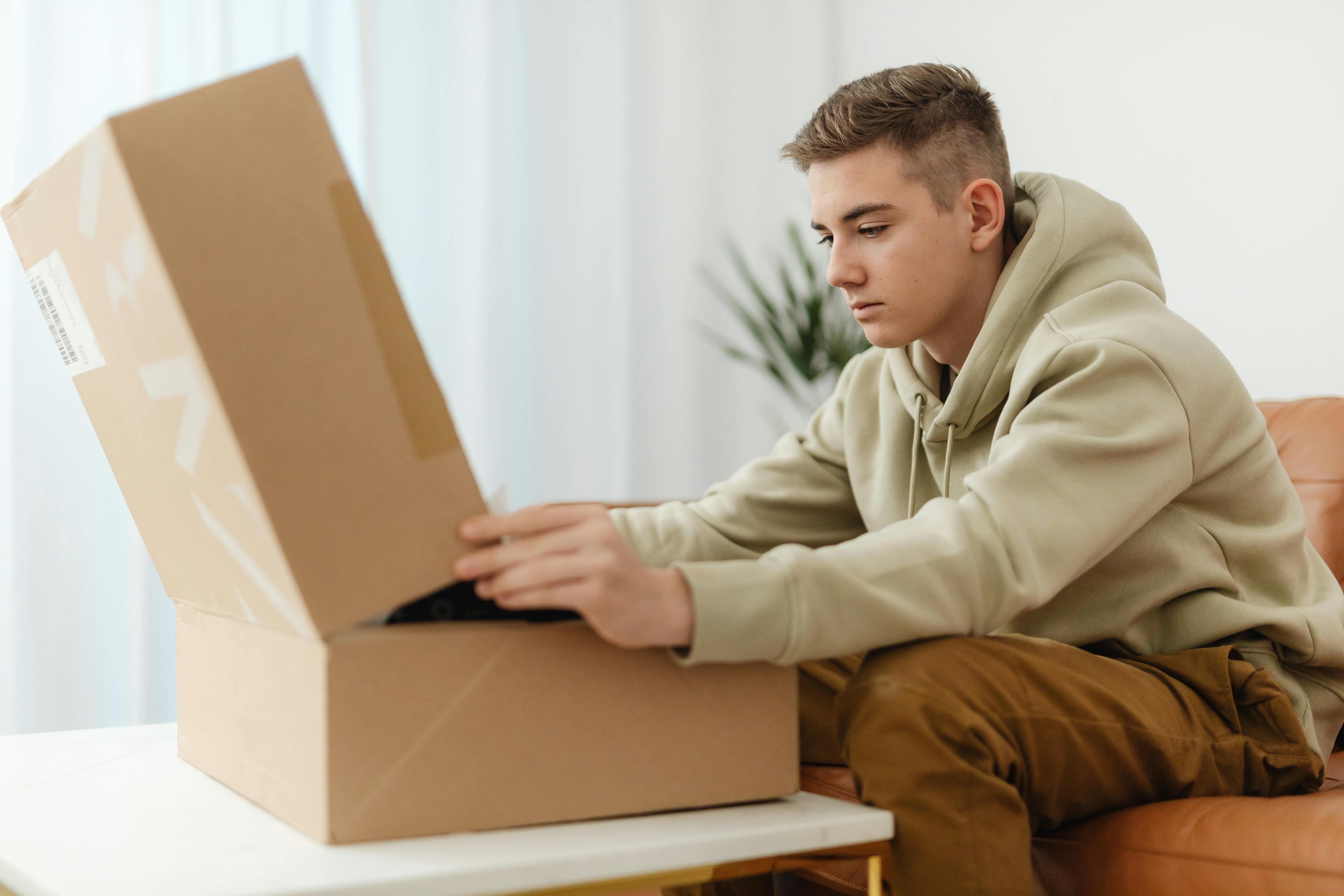 A young man opening eCommerce packaging at home
