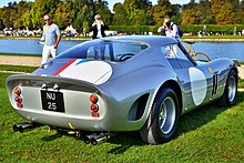 Rear view of a silver sports car parked on grass facing a river