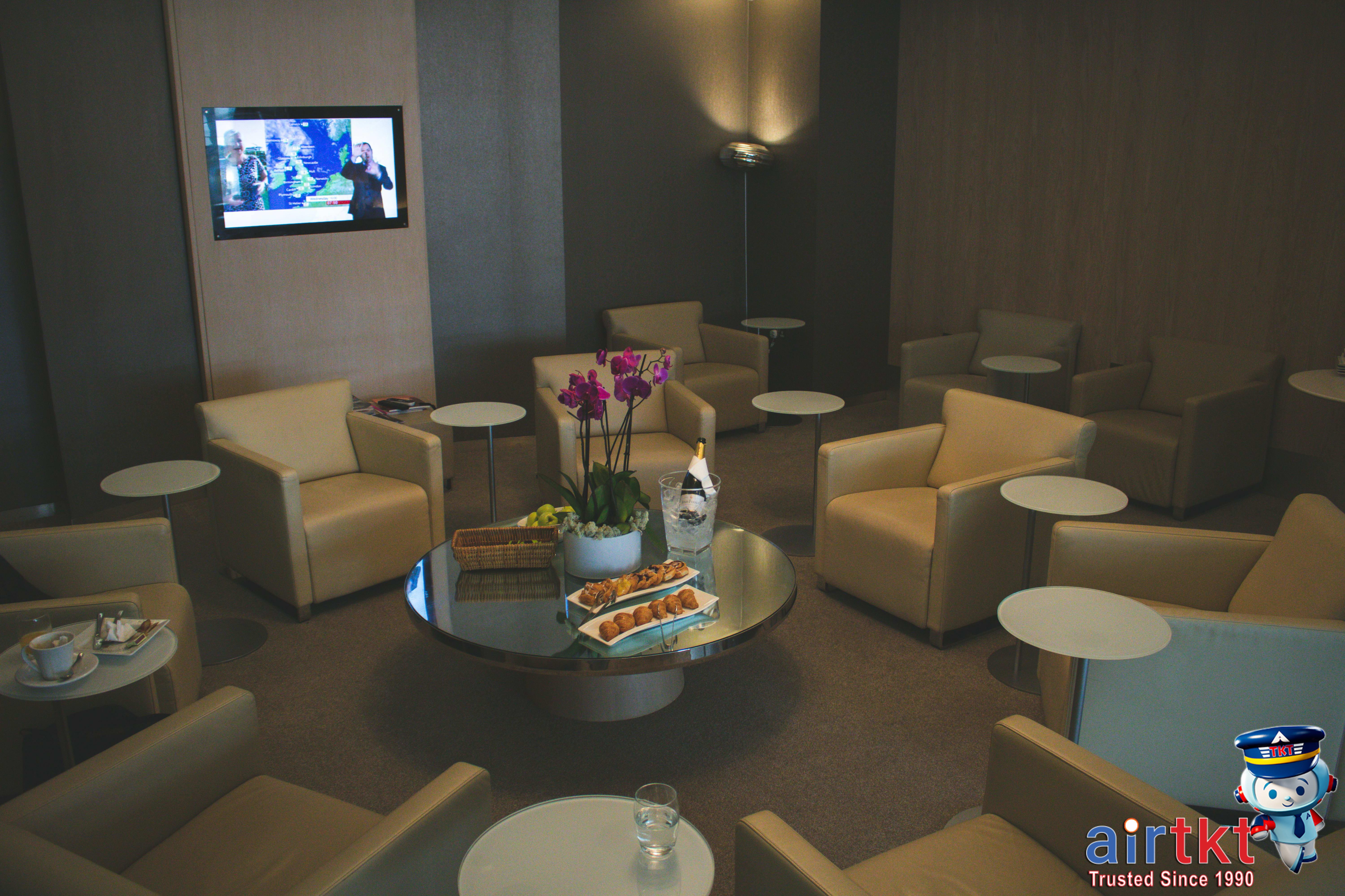 Travelers relaxing in an elegant airport lounge with food and drinks