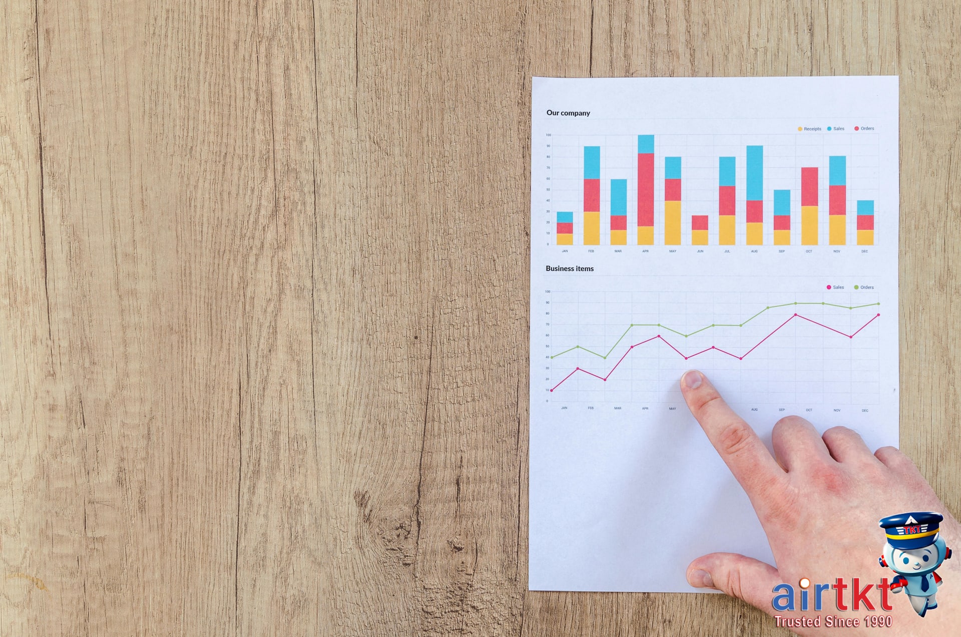 Hand analyzing business graphs on a wooden desk