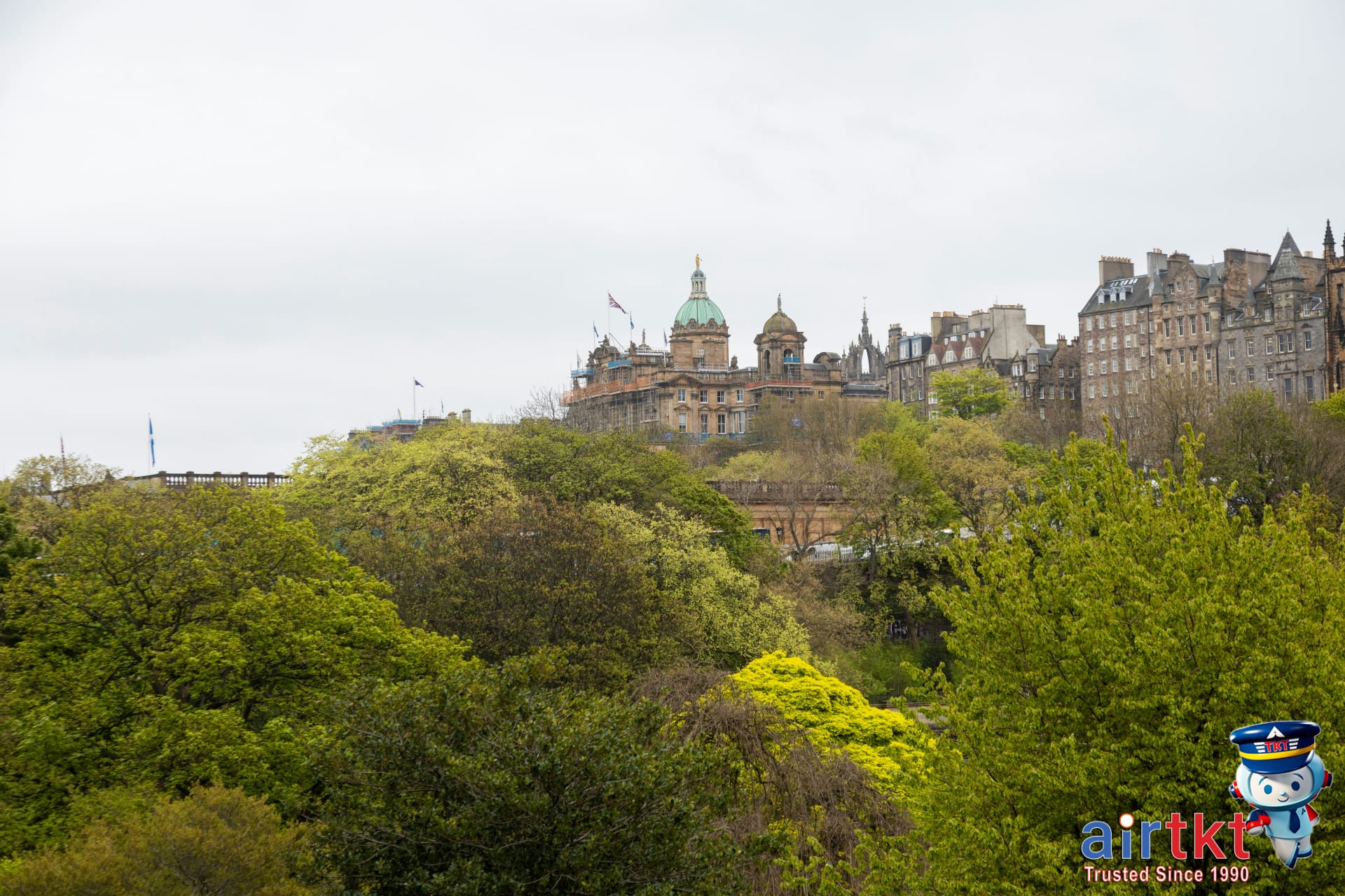 Visitors enjoying greenery in Princes Street Gardens with cityscape background