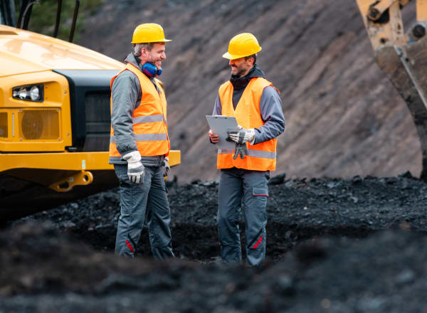 Worker with a plan and a clipboard discussing things in quarry