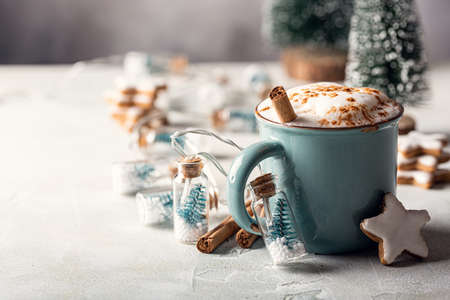 Aromatic cocoa drink with cinnamon and chocolate in blue mug with gingerbread stars cookies with white glaze. winter holidays background with copy space