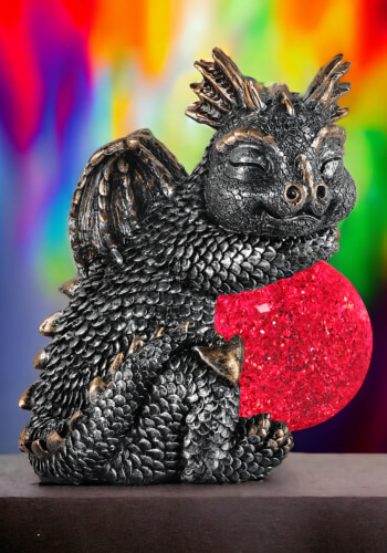 A silver dragon, happily asleep holding a red glitter led ball.