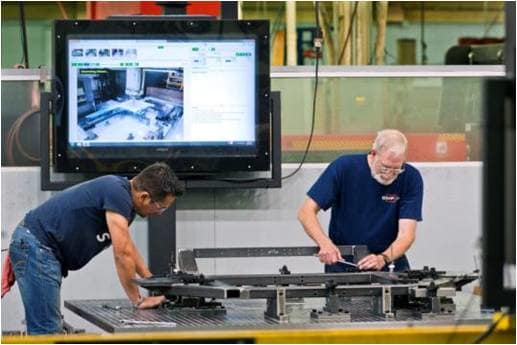 Shop floor operators setting up jigs and fixtures on a machining center with step-by-step procedures. (Image courtesy of Visual Knowledge Share.)