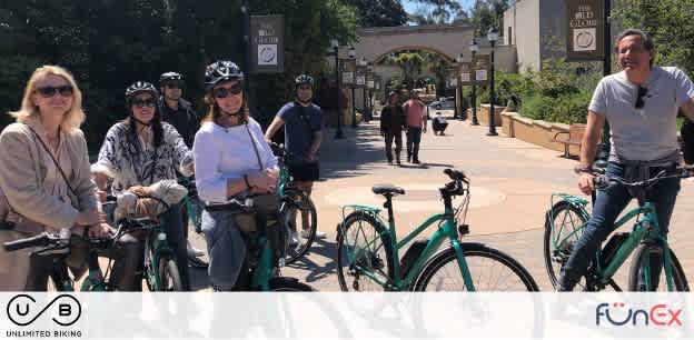 Image description: A group of five individuals is smiling and posing with bicycles on a sunny day. They are standing on a paved pathway that leads through a park-like setting with trees and a clear blue sky in the background. The group consists of a diverse mix of men and women, each wearing casual and comfortable outdoor attire suitable for biking, with some wearing helmets for safety. Two of the bicycles are parked in the foreground with a third bike visible in the background between the participants. The surrounding area has a relaxed, recreational atmosphere with other park visitors visible walking in the background. The logo "FunEx.com" along with the text "UNLIMITED BIKING" is present at the bottom of the image, indicating an emphasis on outdoor leisure activities.

As well, FunEx.com is excited to offer unbeatable discounts, ensuring our customers enjoy the lowest prices on tickets for their next adventure.