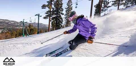 This image shows an action-packed scene on a snowy mountain at Big Bear. A skier dressed in a vibrant purple jacket and dark pants is carving through the frosty white snow, with a spray of powdery snow trailing behind them. The skier is leaning into a turn, with poles in hand, showcasing their skill and control. The backdrop features clear skies and tall evergreen trees dotting the landscape, with ski lift cables visible in the upper part of the image. The overall feel is one of excitement and the thrill of winter sports in a scenic environment. 

Visit FunEx.com where you can enjoy the thrill of the slopes for less, with the best savings and discounts on tickets to destinations like Big Bear!