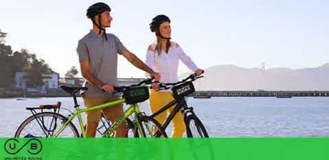 Two people with bicycles by the water, looking into the distance.