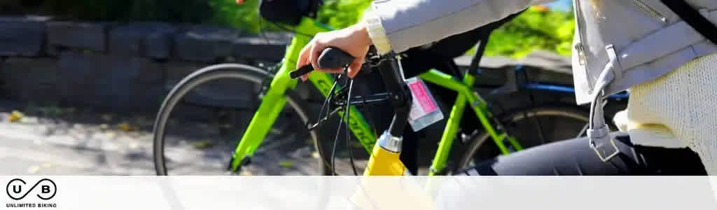 This image displays a person on the left side preparing for a bike ride during daylight hours. The focus is on the individual's hands which are gripping the handlebars of a green bicycle, one hand engaged with the brake lever. The rider appears to be wearing a white helmet, green pants, and is holding a yellow item that may be a lock or a light. The bicycle stands on a path, indicative of a park or urban area designed for cycling or recreation and there's lush greenery blurred in the background. In the foreground, the path appears to be concrete or light-colored pavement. A logo at the top left corner reads "UNLIMITED BIKING" suggesting that the image promotes cycling activities or a bike rental service.

Visit FunEx.com to snag the lowest prices and fantastic discounts on tickets for your next adventure, ensuring that you maximize your savings while enjoying limitless biking fun!