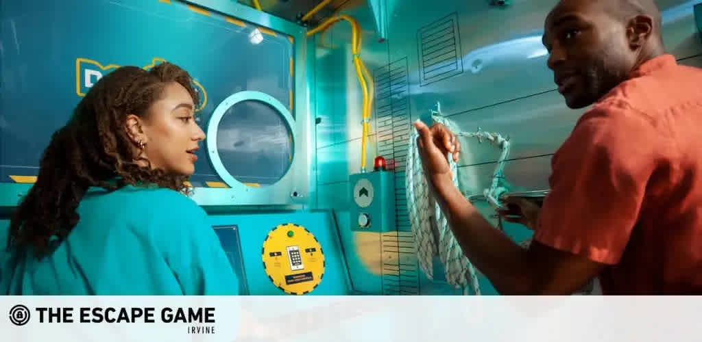 This image depicts an exciting and interactive experience at The Escape Game Irvine. It features two individuals inside a room designed to look like the interior of a submarine, with a vibrant aqua-blue color scheme and thematic elements that simulate a naval environment. On the left, a woman with her hair pulled back observes a round window reminiscent of a ship's porthole. She wears a teal top that complements the room's color. To the right, a man in a red shirt is focused on untangling or manipulating what appears to be a net or a series of ropes attached to the wall. Both individuals appear engaged and are working together to solve a puzzle or complete a challenge as part of the escape game.

Experience the thrill of strategy and teamwork with discounted tickets to The Escape Game. Take advantage of our savings to unlock the lowest prices for an unforgettable adventure!