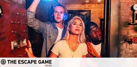 This image depicts a group of three individuals engaged in an escape room game with determined expressions. They are in a dimly lit room that resembles a rustic vault or cellar accentuated with warm ambient lighting. The person in the foreground, a woman with blonde hair, looks onward with focus. Behind her to the left, a man with his arm extended upwards reaches for something above, whilst another man to her right peers over her shoulder with an attentive gaze. The setting hints at an adventurous and immersive atmosphere. A watermark at the bottom of the image reads "THE ESCAPE GAME IRVINE."

Experience the thrill of the escape room adventure and enjoy the excitement with your friends, all while benefiting from our exclusive discounts, ensuring you get the lowest prices on tickets at FunEx.com.