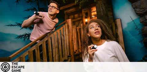 This image features two individuals engaged in an interactive and immersive experience at The Escape Game. On the left, a man with glasses is shown aiming a flashlight towards something out of the frame, his expression focused and determined. He is wearing a checkered shirt and appears to be searching for clues or pathways. On the right, a woman with her hair tied back looks up with an expression of surprised curiosity. She holds a small object in her hand that could be a part of the game. Both participants are standing on a wooden staircase that suggests a rustic or outdoor-themed setting, contributing to the adventurous ambiance of the game. The lighting and the wood elements exude an eerie yet exciting atmosphere, capturing the essence of suspense that escape games are known for.

Remember, by booking with FunEx.com, you not only guarantee an unforgettable adventure but also enjoy the excitement with the promise of unmatched savings on tickets.