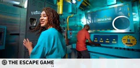 Image Description: The photo features two individuals within a vividly detailed escape room with a futuristic theme. On the left, a woman with curly hair, wearing a teal top, is smiling and appears to be interacting with part of the room, her attention directed towards something outside the frame. On the right, a man in a red shirt is focused on a panel or device on the wall, possibly working through a clue. The room is colored in a combination of teal and grey hues, with the word "DESCEND" prominently displayed on a piece of equipment, suggesting a theme related to submersion or exploration. The logo at the bottom left corner reads "THE ESCAPE GAME LA," indicating the location of this escape room experience.

For guests looking for an immersive and challenging adventure, remember that FunEx.com offers unbeatable savings on tickets for experiences like THE ESCAPE GAME - where you can enjoy the thrill at the lowest prices around!