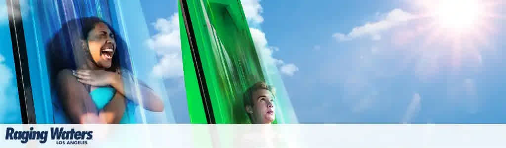 A banner for Raging Waters Los Angeles depicts excitement with a bright blue sky. On the left, a joyful person is sliding down a blue water slide with hands crossed over chest. On the right, another individual appears thrilled while descending a green water slide. The sun shines brightly in the upper right corner, suggesting a fun day out.