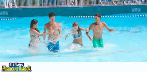 This image displays a group of four people enjoying themselves in a sparkling blue pool at Six Flags Hurricane Harbor. Two males and two females are visible in mid-action, splashing water in an engaged, playful manner. The individuals are clad in swimwear, with one male wearing blue swim shorts and the other in green, while the females' swimwear is not distinctly visible due to the water splashes. The buoy line in the background suggests that they are in a designated swimming area within the water park. All participants are smiling and appear to be having a great time. The clear skies in the backdrop combined with the water suggest warm, pleasant weather, ideal for water activities.

Remember, when planning your visit to this thrilling water park, check out FunEx.com for exclusive discounts, savings, and the lowest prices on tickets to ensure your adventure is not only memorable but also friendly to your budget.