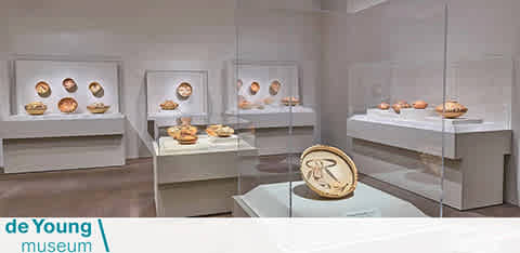 This image features an interior view of the de Young museum, showcasing an exhibition room with a modern and minimalist design. The walls are painted a neutral white, and the floor seems to be a polished light grey or beige. The room is well-lit, creating an inviting atmosphere to observe the displayed artifacts. Several wall-mounted, glass-encased displays each house a series of spherical objects that appear to be artistic or historical in nature. In the center of the room is a glass table displaying a large circular artifact with intricate designs, which stands out as a centerpiece.

Directly below the central table, there is a transparent enclosure that might contain additional information about the exhibit or a specific piece. This layout suggests an environment that is accessible to visitors, allowing them to navigate easily and get up close to the exhibits while maintaining their preservation.

FunEx.com is committed to providing you with an enjoyable and affordable experience, offering the lowest prices and biggest savings on tickets, so you can explore cultural treasures like the de Young museum without stretching your budget.