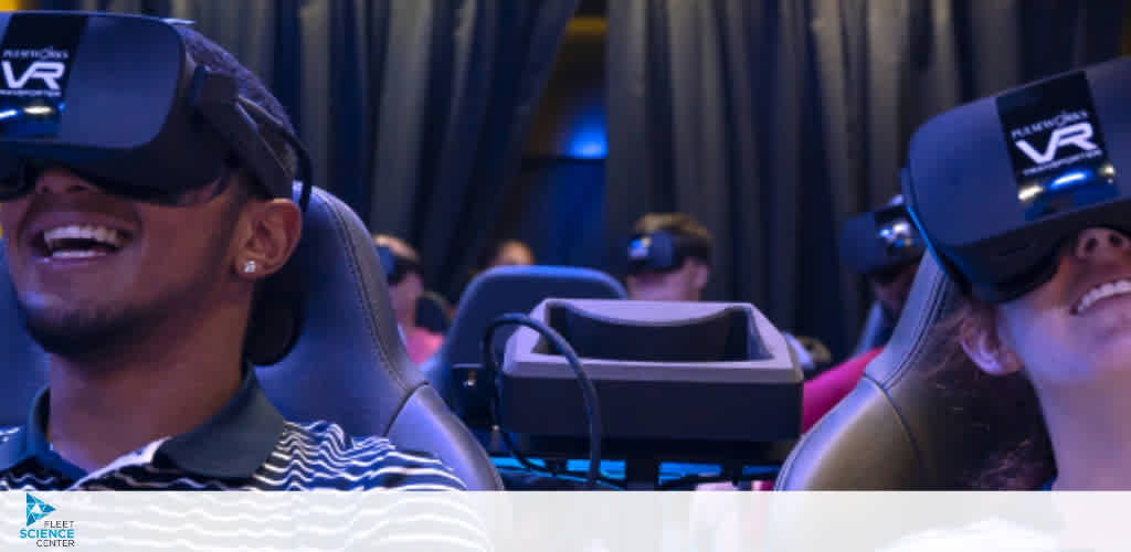 Image Description: This image captures a group of individuals engaged in a virtual reality (VR) experience. They are seated in comfortable-looking chairs that seem to be part of a simulator setup, specifically designed for VR engagement. Both males and females are represented, with one prominently featured man and woman in the foreground. They are both wearing VR headsets and are turned slightly upwards, their facial expressions reflecting amusement and enjoyment. The room is dimly lit, suggesting a focus on the screens contained within their headsets. The VR headsets have the logo "RAVEN" written on them, indicating the brand. The place is identified as the "Fleet Science Center" via a watermark on the image, suggesting an educational or entertainment venue that offers interactive experiences.

At FunEx.com, we invite you to immerse yourself in virtual worlds at the best possible rates. Remember to check out our exclusive offers for the lowest prices on tickets and maximize your savings as you step into your next virtual adventure.