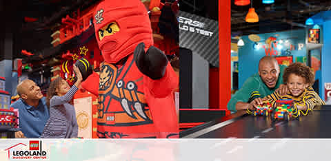 This image features a joyful scene at a LEGOLAND Discovery Center. A person dressed as a LEGO ninja character, predominantly red with black and yellow accents, is standing to the left with their hand raised in a friendly greeting. On the right, a man and a young child are interacting playfully with LEGO bricks on a table, both appear delighted and engaged in the moment. The background shows a vibrant, colorful indoor setting with the LEGO theme, and the red LEGOLAND logo is visible at the bottom left corner of the photo. Remember, at FunEx.com, we offer the joy of family-friendly adventures at the lowest prices, ensuring that you get the best value on tickets, alongside significant savings.