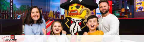This image displays a cheerful family of four posing with a life-sized LEGO character at LEGOLAND. On the left side, a woman with shoulder-length hair and a blue top is smiling alongside a young girl with light-colored hair who is joyfully open-mouthed. Next, a boy with dark hair is grinning, and on the far right, a man with short hair and a beard is also smiling. They are standing in front of a colorful LEGOLAND backdrop. The LEGO character in the center is dressed as a pirate, with a large hat, black eye patch, and traditional pirate attire in bright primary colors.

Experience the excitement and create family memories at LEGOLAND, and remember, at FunEx.com, we offer the lowest prices and amazing savings on tickets for your next adventure.