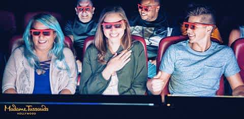 A group of five young friends enjoying a fun day at the movies wearing 3D glasses and smiling inside a theater.