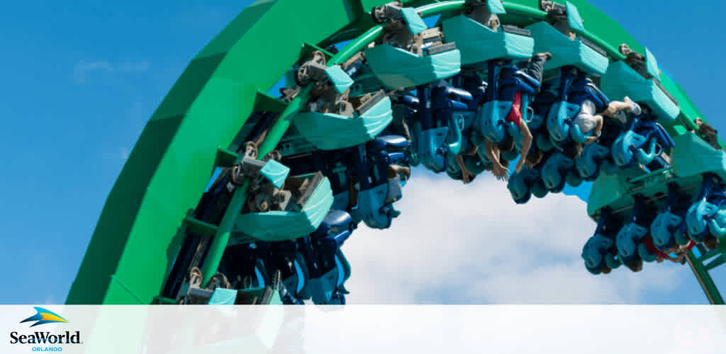 Thrill-seekers experience an adrenaline rush on a roller coaster, inverted at the pinnacle of a loop. The blue seats with secure over-the-shoulder restraints hold excited riders, feet dangling against a clear sky. SeaWorld Orlando's logo embellishes the photo, suggesting the location of this exhilarating ride.