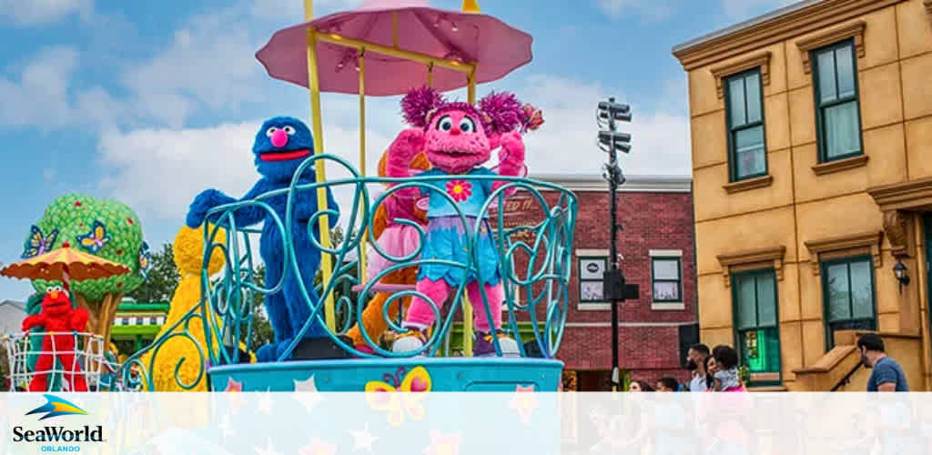 Image featuring a colorful parade float at SeaWorld Orlando with vibrant Sesame Street characters. The float is adorned with bright patterns and umbrellas, conveying a festive atmosphere. Characters, resembling puppets, wave to onlookers against a backdrop of stylized city buildings under a blue sky scattered with clouds. Visitors nearby enjoy the lively event.