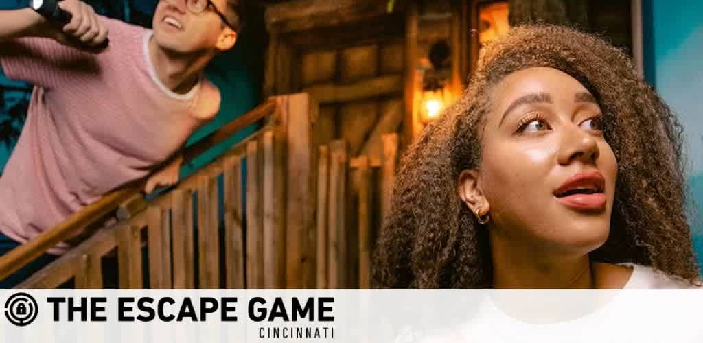 A promotional banner for The Escape Game featuring a curious woman in the foreground and a man in the background descending stairs, both engaged and looking in different directions, reflecting the excitement of an escape room adventure. The company's logo is prominently displayed, suggesting a location in Cincinnati.