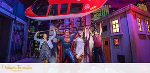 Four people posing with a Superman figure at a themed exhibit.