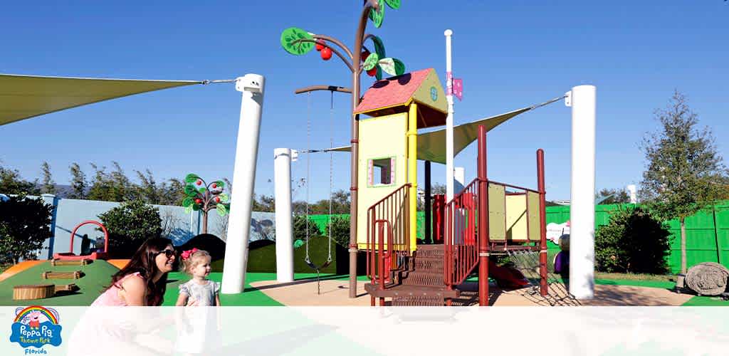 A playground with colorful equipment and sunshades, featuring an adult and child.